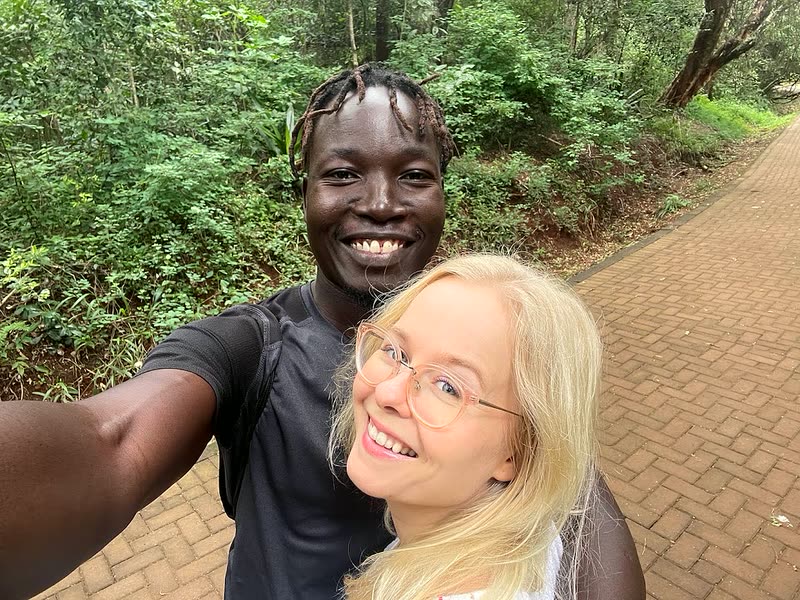 Aino and Joshua smiling in a selfie on a forest path