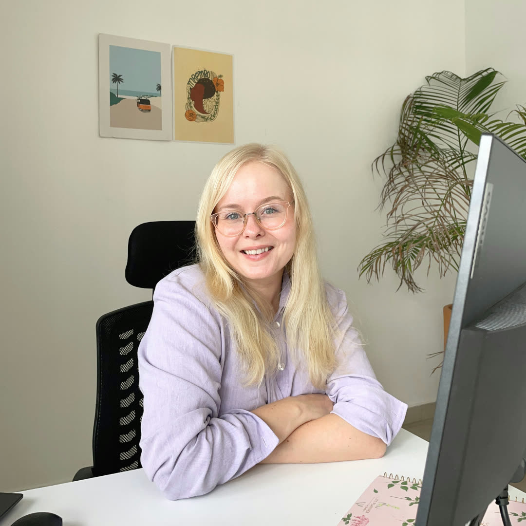 Aino smiling at her desk next to her monitor