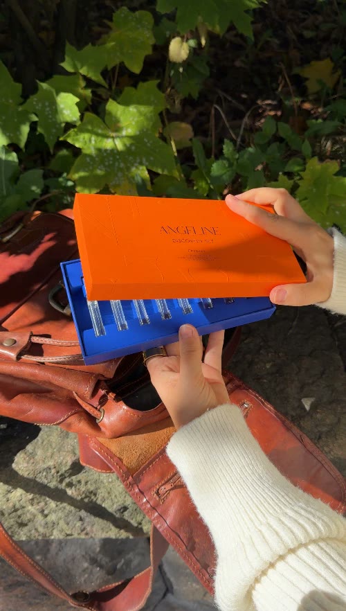 Hands opening an orange Angeline Perfume discovery box
